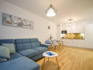ein Wohnzimmer mit einem blauen Sofa und einer Küche in der Unterkunft Apartament Bliżej Morza in Kołobrzeg
