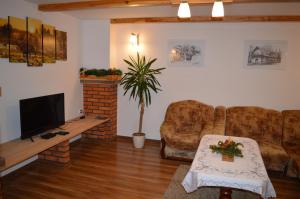 a living room with a flat screen tv and two chairs at Domek pod Majową Górą in Kacwin