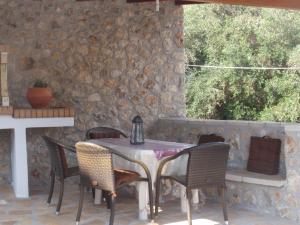 a table and chairs on a patio with a stone wall at Korina Studios in Paleokastritsa