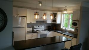 a kitchen with white appliances and a black counter top at Condo Lac Archambault 295 in Saint-Donat-de-Montcalm