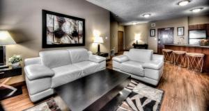 a living room with two white chairs and a table at Grand Inn & Residence- Grande Prairie in Grande Prairie