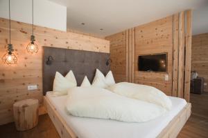 sypialnia z białym łóżkiem i drewnianą ścianą w obiekcie Bauernhofresidence Leierhof w mieście Rodeneck