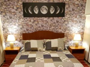 1 dormitorio con pared de piedra, 1 cama y 2 lámparas en Hostal Torres del Paine 2 en Punta Arenas