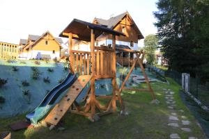 a wooden playground with a slide in a yard at Apartament Nad Potokiem in Szczawnica