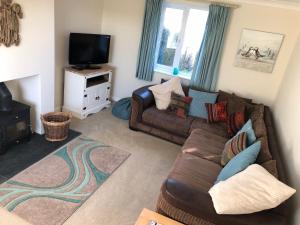 a living room with a couch and a tv at 2 Fernleigh Villas in Perranporth