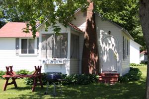 a house with a grill and a picnic table in the yard at Eden Village Motel and Cottages in Bar Harbor