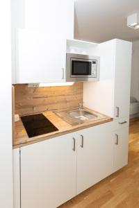 uma cozinha branca com um lavatório e um micro-ondas em My room serviced apartment-Messe em Munique