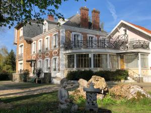 una casa grande con una estatua delante de ella en La villa rochette en Forges-les-Bains