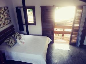1 dormitorio con cama blanca y balcón en Nalu Guest House en Ubatuba