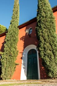 a red building with a green door and two trees at Tenuta Col di Sasso in Scarlino