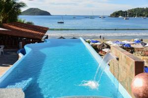 una piscina con una fuente de agua al lado de una playa en Arena Suites, en Zihuatanejo