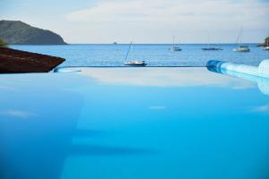a swimming pool overlooking the ocean with boats in the water at Arena Suites in Zihuatanejo