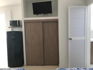 Una sala de estar con televisión y una puerta de madera. en Cavas AP, en Cali