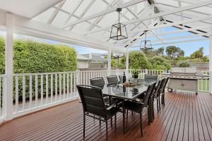 a white pergola on a deck with a table and chairs at Sorrento Beach Escape in Sorrento
