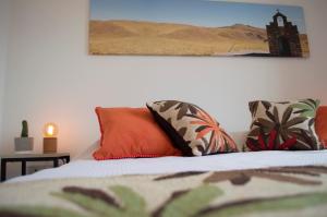 1 cama con almohadas de color naranja y una foto en la pared en Cactus 1 en Salta