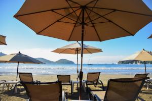 a group of chairs and umbrellas on a beach at Arena Suites in Zihuatanejo