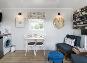 a living room with a table and a clock on the wall at Blackbird Cottage in Lincoln