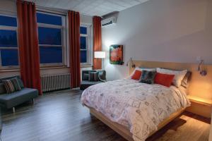 a bedroom with a bed and a chair and windows at Suite Marie-Thérèse in Vallée-Jonction