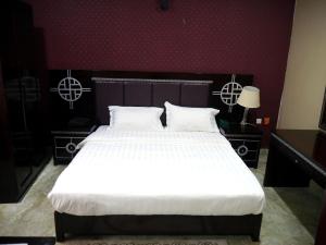 a bedroom with a large bed with white sheets at Porto Golf Hotels in Kano