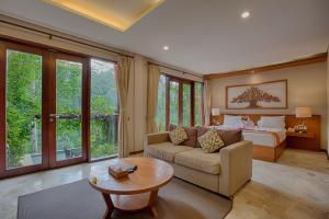 a bedroom with a bed and a couch and a table at Anahata Villas and Spa Resort in Ubud