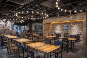 a restaurant with wooden tables and chairs and a brick wall at Hotel Mystays Kagoshima Tenmonkan in Kagoshima