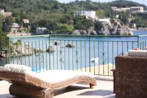 a wicker chair sitting on a balcony overlooking a body of water at Akis Apartments in Paleokastritsa