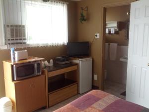 a bedroom with a microwave on a desk with a television at Motel Montgolfière JP in Saint-Jean-sur-Richelieu