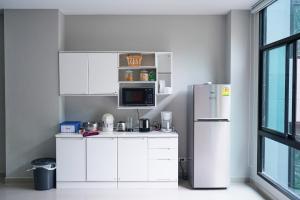 a kitchen with white cabinets and a refrigerator at Baan Pakdi Pattaya in Pattaya Central
