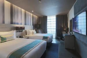 宿务bai Hotel Cebu的一间有两张床和一台平板电视的酒店房间