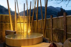 a hot tub on a deck with a wooden fence at Shima Onsen Kashiwaya Ryokan in Nakanojo