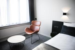 a bedroom with a bed and a chair and a table at Hotel Carnac in Koksijde