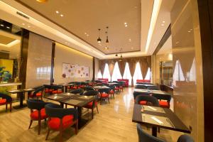 a dining room with tables and red chairs at Novotel Daqing Haofang in Daqing
