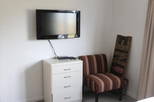 a bedroom with a dresser and a tv and a chair at Beach across the road in Waihi Beach