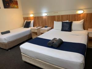2 Betten in einem Hotelzimmer mit Handtüchern darauf in der Unterkunft Wattle Tree Motel in Cootamundra