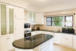 una cucina con armadi bianchi e ripiano in granito di Villa 37 on Westridge a Durban