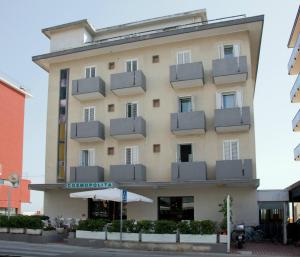 un bâtiment d'hôtel avec un parasol devant lui dans l'établissement Hotel Cosmopolita, à Rimini