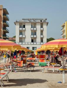 里米尼的住宿－四海酒店，一个带椅子和遮阳伞的海滩和一座建筑