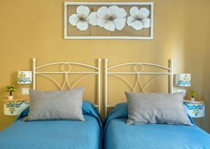 a bedroom with two beds with blue sheets and flowers on the wall at Regina Elena in Naples