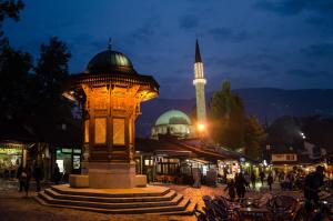 una torre del reloj en medio de una ciudad por la noche en Design Atelier, en Sarajevo