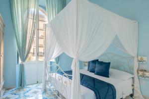 1 dormitorio con cama con dosel, paredes azules y ventana en Regina Elena, en Nápoles