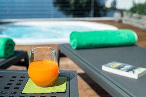 a glass of orange juice sitting on a table next to a pool at Villa Poseidon in Porto Valtravaglia