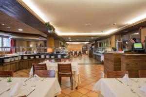 un restaurant avec des tables et des chaises blanches et un bar dans l'établissement Hotel Màgic Ski, à La Massana