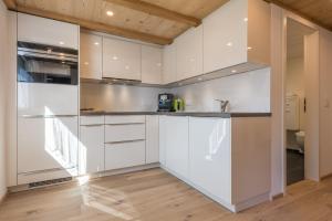 a kitchen with white cabinets and a wooden floor at Haus Bergsonne in Saas-Almagell