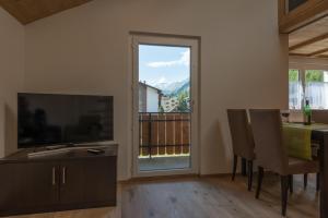 Haus Bergsonne في ساس-الماغيل: غرفة معيشة مع تلفزيون وطاولة مع كراسي