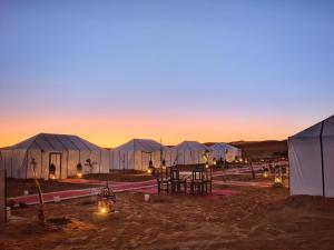 a group of tents in the desert at sunset at Sahara Majestic Luxury Camp in Merzouga