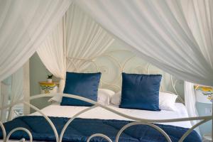 1 cama con almohadas azules y dosel blanco en Regina Elena, en Nápoles