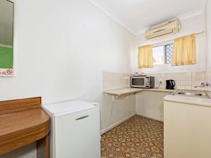 a kitchen with a sink, stove, and refrigerator at Riviera Motel Bundaberg in Bundaberg