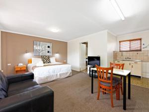 1 dormitorio con cama, mesa y sofá en Riviera Motel Bundaberg en Bundaberg