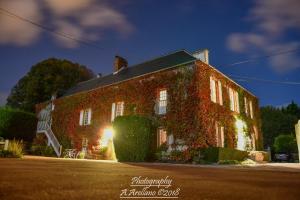 a brick building with ivy growing on it at night at La Faisanderie in Grandcamp-Maisy