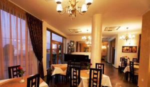 a dining room with tables and chairs and a chandelier at Pension Casa Grande in Baile Felix